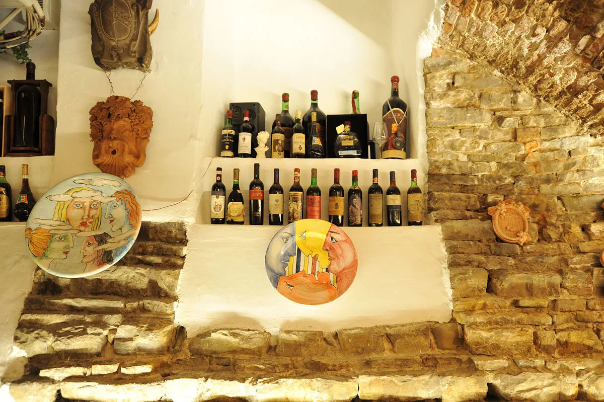 Wine bottles and decorative plates on the cellar’s stone walls